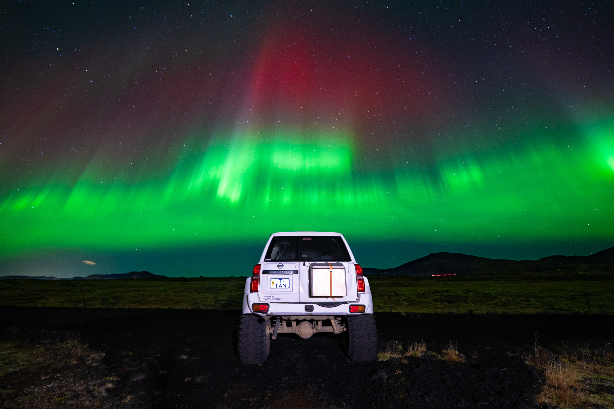 Superjeep beneath vibrant Northern Lights